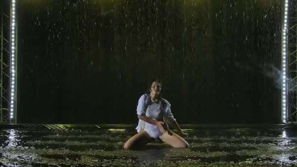 Mladá žena se eroticky pohybuje po hladině vody v dešti. — Stock video