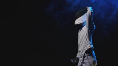 Genç bir adamın yan görüntüsü, bir eskrim atleti maske takıyor ve dövüş pozisyonuna geçiyor. Siyah dumanlı arka plan. Ağır çekim. Kapat..