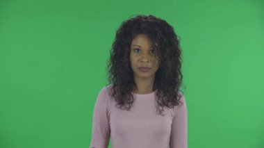 Güzel Afrikalı Amerikalı genç bir kadının portresi kameraya bakıyor ve kafasını negatif sallıyor. Bu tabletleri tavsiye etmiyor. Yanan esmer, kot pantolonlu dalgalı saçlı ve bej bluzlu.