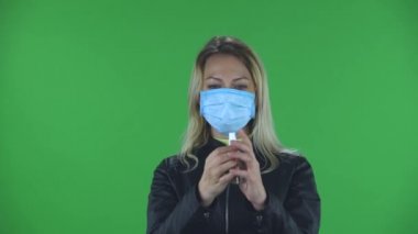 Tıbbi koruyucu yüz maskeli güzel bir kadının portresi kameraya bakıyor ve Coronavirus 'un yayılmasını önlemek için ellerine antiseptik uyguluyor. Sarışın, gevşek saçlı.