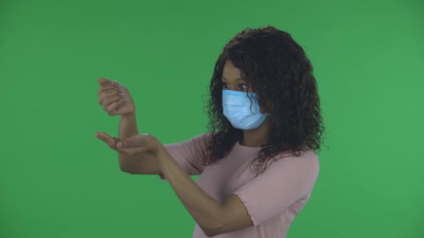 A gyönyörű afro-amerikai fiatal nő portréja orvosi védőmaszkban kézről kézre önti a gyógyszert, hogy megelőzze a koronavírus terjedését. Égő barna, hullámos hajjal — Stock videók