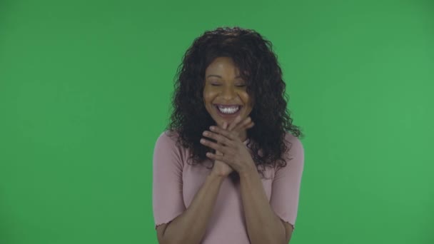 Retrato de una hermosa joven afroamericana sonríe con alegría feliz. Morena ardiente con el pelo ondulado en jeans y una blusa beige en una pantalla verde en el estudio. — Vídeo de stock