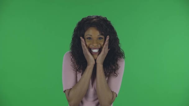 아름다운 아프리카계 미국인젊은 여성의 초상화가 충격과 놀란 표정으로 카메라를 보고 있습니다. 청바지를 입은 웨이브 헤어와 녹색 스크린에 있는 베이지 블라우스와 함께 갈색 갈색 갈색 머리를 태우는 모습 — 비디오