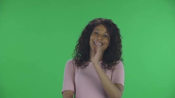 Retrato de la hermosa mujer joven afroamericana está mirando a la cámara y avergonzado. Morena ardiente con el pelo ondulado en jeans y una blusa beige en una pantalla verde en el estudio. — Vídeo de stock