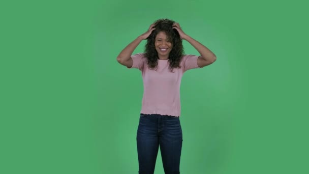 Portret van een mooie Afro-Amerikaanse jonge vrouw die naar de camera kijkt is geschokt en erg overstuur. Brandende brunette met golvend haar in jeans en een beige blouse op een groen scherm in de studio. — Stockvideo