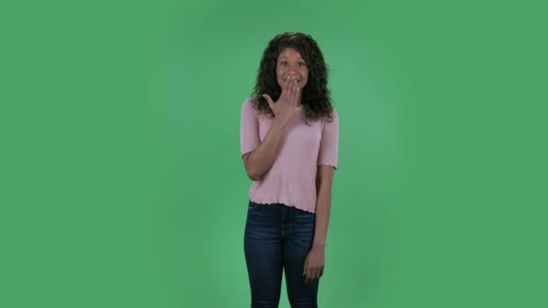 美しいアフリカ系アメリカ人の若い混乱した女性の肖像画は、カメラを見ていると言ってoopsとshrugging.Burningブルネットとともに波状の髪でジーンズとベージュのブラウスでスタジオで緑の画面. — ストック動画