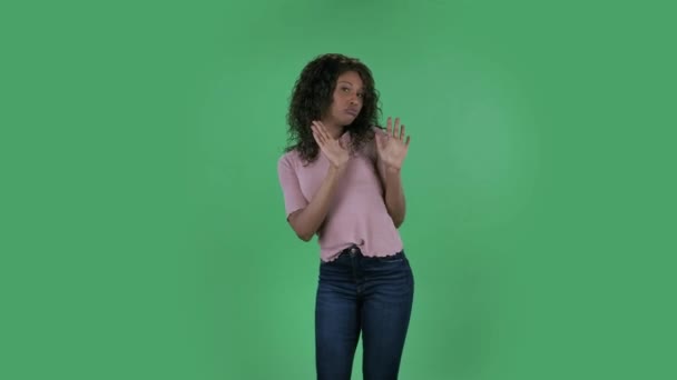 Ritratto di bella afroamericana giovane donna sta guardando la macchina fotografica e ballare divertente. Bruna in fiamme con capelli ondulati in jeans e una camicetta beige su uno schermo verde in studio. — Video Stock