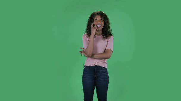 Portrait of beautiful african american young woman is daydreaming and smiling looking up. Burning brunette with wavy hair in jeans and a beige blouse on a green screen in the studio. — Stock Video