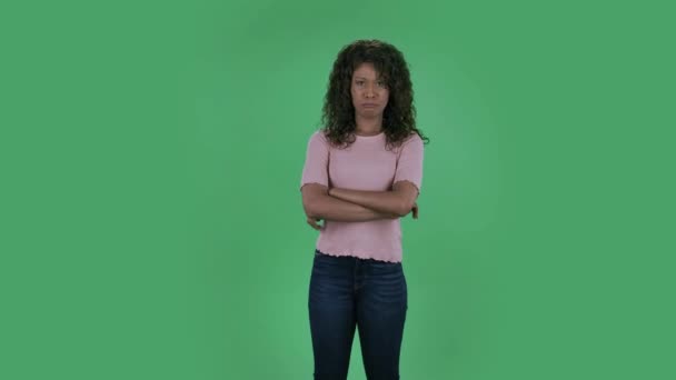 Portrait of beautiful african american young woman is looking at camera is very offended and shrugs shoulders. Burning brunette with wavy hair in jeans and a beige blouse on a green screen in the — Stock Video