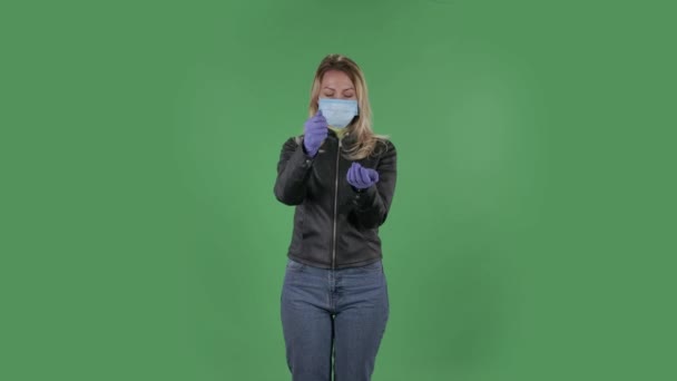 Portrait of beautiful young woman in medical protective face mask pours medicine from hand to hand in order to prevent the spread of coronavirus. Blonde with loose hair in a black jacket and jeans on — Stock Video