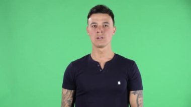 Yakışıklı bir gencin portresi kameraya bakıyor ve dinleniyor ve meditasyon yapıyor. Yeşil Ekran.