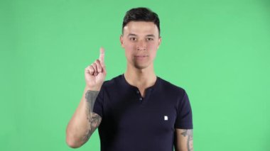 Yakışıklı bir gencin portresi kamera gösterilerine bakıp bir, iki, üç, dört, beş parmağı sayıyor. Yeşil Ekran.