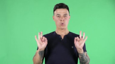 Yakışıklı bir gencin portresi kameraya bakıyor ve dinleniyor ve meditasyon yapıyor. Yeşil Ekran.