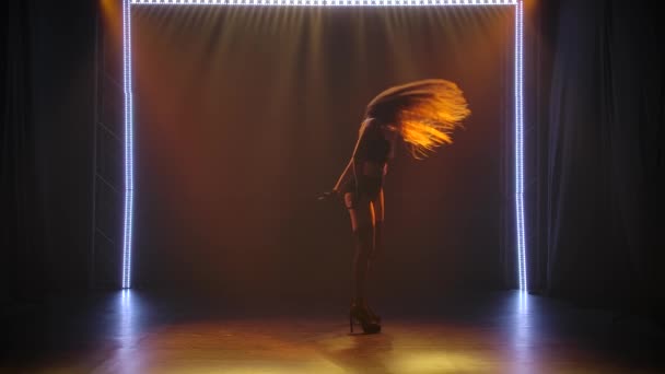 Joven morena caucásica apasionada bailando cautivadoramente en lencería femenina negra en un estudio oscuro con luz escenificada. Silueta de un cuerpo delgado tonificado, cámara lenta. — Vídeos de Stock