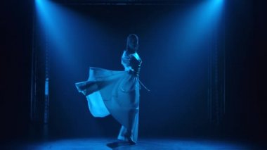 Joan of Arc 'ın suretinde genç ve güzel bir aktris sahnede bir kılıçla dans ediyor. Pırıl pırıl bir başlık takmış ince bir vücudun silueti mavi spot ışıklarının arka planına karşı. Yavaş çekim.