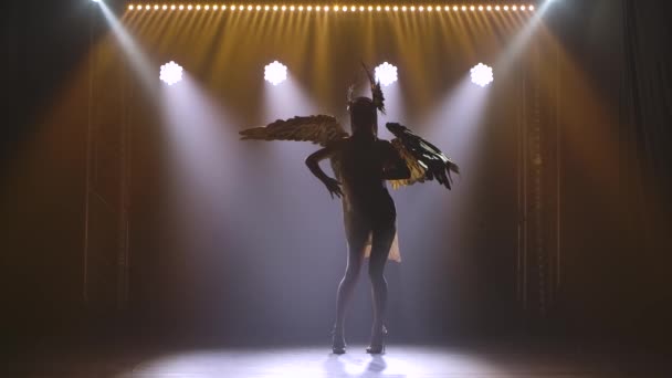 Silhouette of a dancing woman in a short dress and with wings on her back. Greek goddess Artemis in a theatrical vocal dance show with dynamic neon lights. Slow motion. — Stock Video