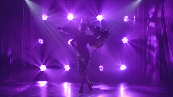 Une belle actrice en costume de la déesse grecque Artémis avec des ailes danse. Silhouette sur fond violet en studio. Mouvement lent. — Video