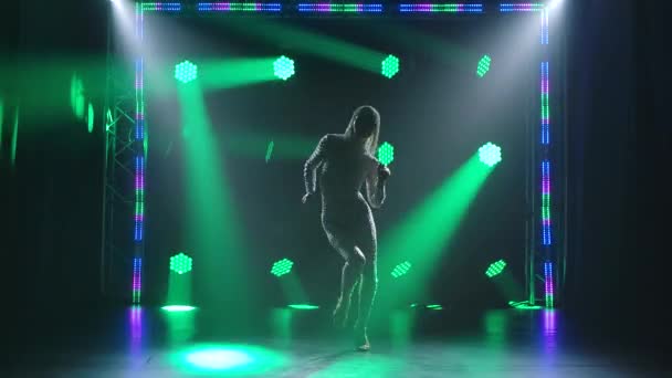 A passionate dance performed by a slender young woman. A female dancer in a tight fitting suit with rhinestones against a background of bright multi-colored spotlights. Slow motion. — Stock Video