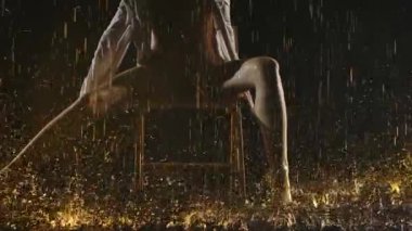 Bej mayo ve gömlek giyen yarı çıplak genç bir kadın sandalyede otururken bacaklarıyla düzgün hareketler sergiliyor. Yağmur altında poz veren çağdaş bir balerin. Ağır çekim. Kapat..