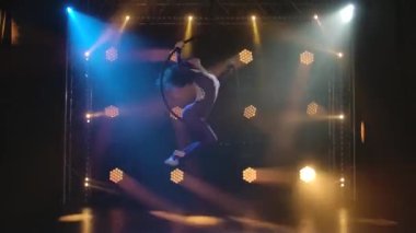 Genç hava sanatçısı kadın bir hava çemberinde hızla dönüyor. Dinamik neon ışıkları olan karanlık bir stüdyoda çekildi..