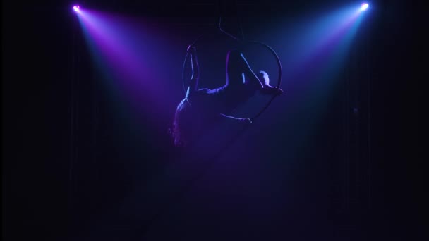 Delar av garn och balansering utförs av en kvinnlig antenn akrobat på en luftring. Silhuetter i rampljuset. — Stockvideo