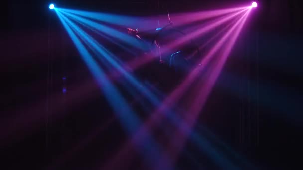 Young adult woman using aerial hoop, making flexibility twine exercise in air. An aerialist is silhouetted in dynamic beautiful neon lights. — Stock Video