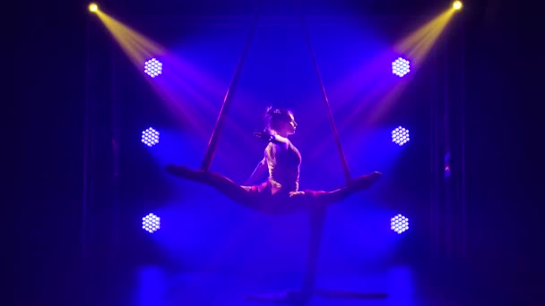 Une jeune artiste de cirque talentueuse effectue un équilibrage sur la soie aérienne. Chaussure acrobatique dans un studio sombre avec néons bleus. Gros plan. — Video