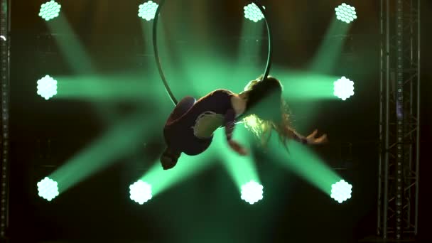 Air gymnastika provádí akrobacii triky na letecké obruče. Vzrušující akrobatické představení v tmavém studiu se zeleným jevištním osvětlením. Zavřít. — Stock video