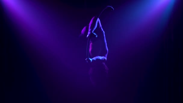 Professional aerial gymnast female rotates on an air hoop. Silhouette of an attractive woman in the rays of studio light on a black background. Close up. — Stock Video