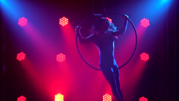 Mujer silueta haciendo truco acrobático en aro aéreo. Filmado en un estudio oscuro en el centro de atención rojo. De cerca.. — Vídeos de Stock