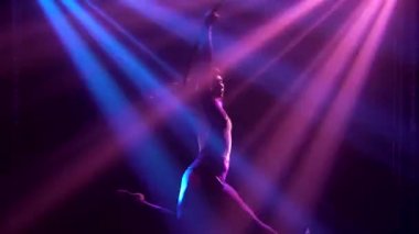 Esnek atletik sirk jimnastikçisi hava halkası üzerinde akrobatik elementler sergiliyor. Dinamik spot ışığında karanlık bir stüdyoda çekildi. Kapat..