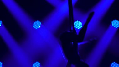 Genç bir kadın hava ipeği üzerinde sicim çalışması yapıyor. Mavi ışıkta ince, esnek bir siluet. Kapat..