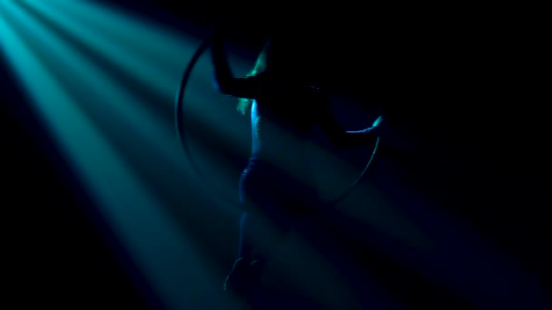 Graceful performance of the flexible female artist of the circus on the air ring under the dome. Silhouette of a slim body in a tight fitting suit in magical rays of light. Close up. — Stock Video