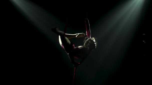 Acrobatic performance of a young female performer circus on air silk. A silhouette of a woman whirls in the air with backlight. Close up. — Stock Video