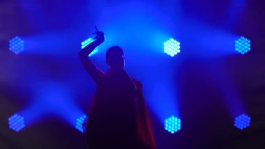 Siluet kırmızı sari giymiş genç bir kadın dansçı. Hint halk dansı. Duman ve mavi neon ışıklarıyla karanlık bir stüdyoda çekildi..