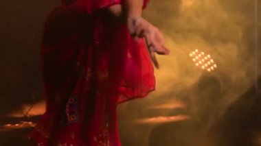 Kırmızı sarili genç bir bayan dansçı. Hint halk dansı. Dumanlı ve sarı neon ışıklı karanlık bir stüdyoda çekildi. Kapat..
