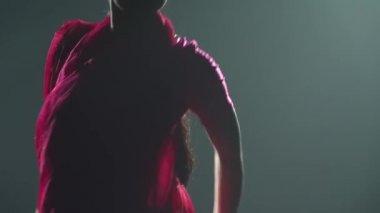 Siluet kırmızı sari giymiş genç bir kadın dansçı. Hint halk dansı. Duman ve neon ışıkla karanlık bir stüdyoda çekildi. Dansçılar elleri ve ayakları yakın.