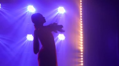 Siluet kırmızı sari giymiş genç bir kadın dansçı. Hint halk dansı. Karanlık bir stüdyoda duman ve neon ışıkla çekildi..