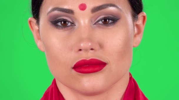 Retrato de la hermosa mujer india está mirando a la cámara coquetea, levanta las cejas, guiña y sopla un beso. Pantalla verde. De cerca. Disparos macro. — Vídeo de stock