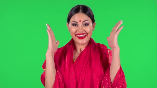 Portrét mladé indické ženy v národním klasickém červeném sárí vypadá přímo s velmi šťastným a radostným výrazem ve tváři. Zelená obrazovka. — Stock video