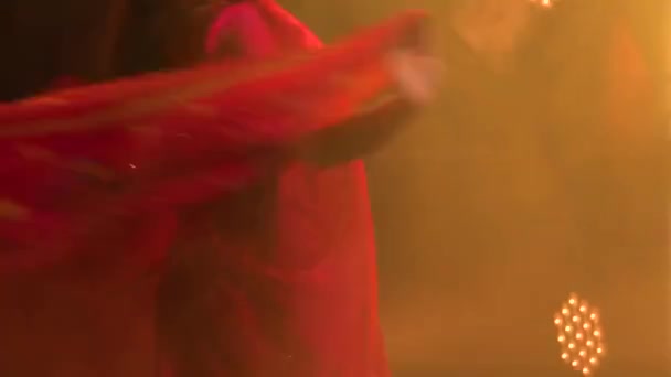 En ung kvinnlig dansare i en röd sari. Indisk folkdans. Skjuten i en mörk studio med rök och gult neonljus. Närbild. — Stockvideo