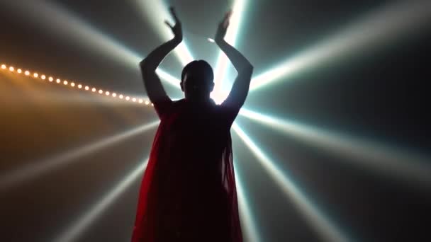 Silhouette une jeune danseuse dans un sari rouge. Danse populaire indienne. Tourné dans un studio sombre avec de la fumée et un éclairage au néon. — Video
