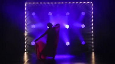Siluet kırmızı sarili genç bir kız dansçı. Hint halk dansı. Duman ve mavi neon ışıklarıyla karanlık bir stüdyoda çekildi..