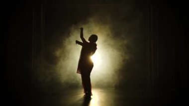 Siluet kırmızı sarili genç bir kız dansçı. Hint halk dansı. Duman ve neon ışıkla karanlık bir stüdyoda çekildi. Yavaş çekim.