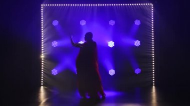 Siluet kırmızı sarili genç bir kız dansçı. Hint halk dansı. Duman ve mavi ışıklı karanlık bir stüdyoda çekildi. Yavaş çekim.