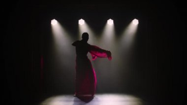 Siluet kırmızı sarili genç bir kız dansçı. Hint halk dansı. Duman ve neon ışıkla karanlık bir stüdyoda çekildi. Yavaş çekim.