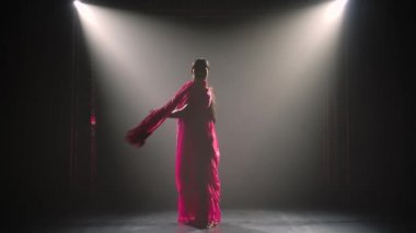 Siluet kırmızı sarili genç bir kız dansçı. Hint halk dansı. Duman ve neon ışıkla karanlık bir stüdyoda çekildi..