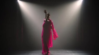 Siluet kırmızı sarili genç bir kız dansçı. Hint halk dansı. Duman ve neon ışıkla karanlık bir stüdyoda çekildi..