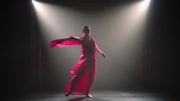 Σιλουέτα μια νεαρή χορεύτρια με κόκκινο σάρι. Ινδικός λαϊκός χορός. Πυροβολήθηκε σε σκοτεινό στούντιο με καπνό και νέον φωτισμό. — Αρχείο Βίντεο