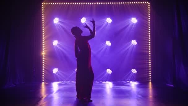 Sylwetka młodej tancerki w czerwonym sari. Indyjski taniec ludowy. Kręcony w ciemnym studiu z dymem i neonowym oświetleniem. Zwolniony ruch. — Wideo stockowe